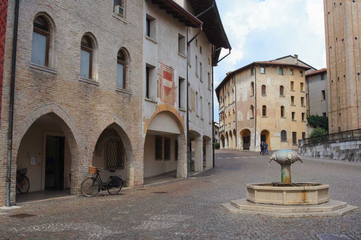 Vista del Corso porticato rinascimentale di Pordenone, con gente che partecipa a eventi culturali.