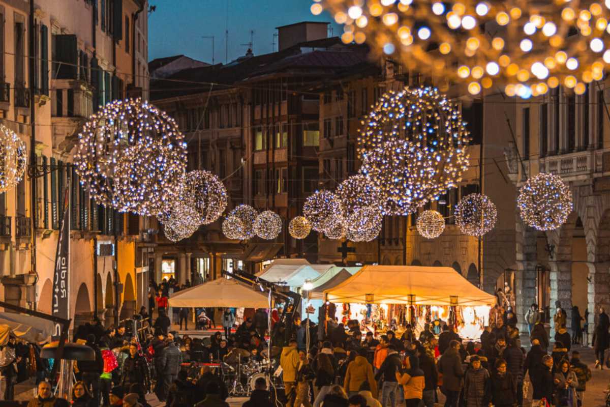 Mercatini di Natale a Udine con luci e bancarelle festive, mostrando l'atmosfera natalizia