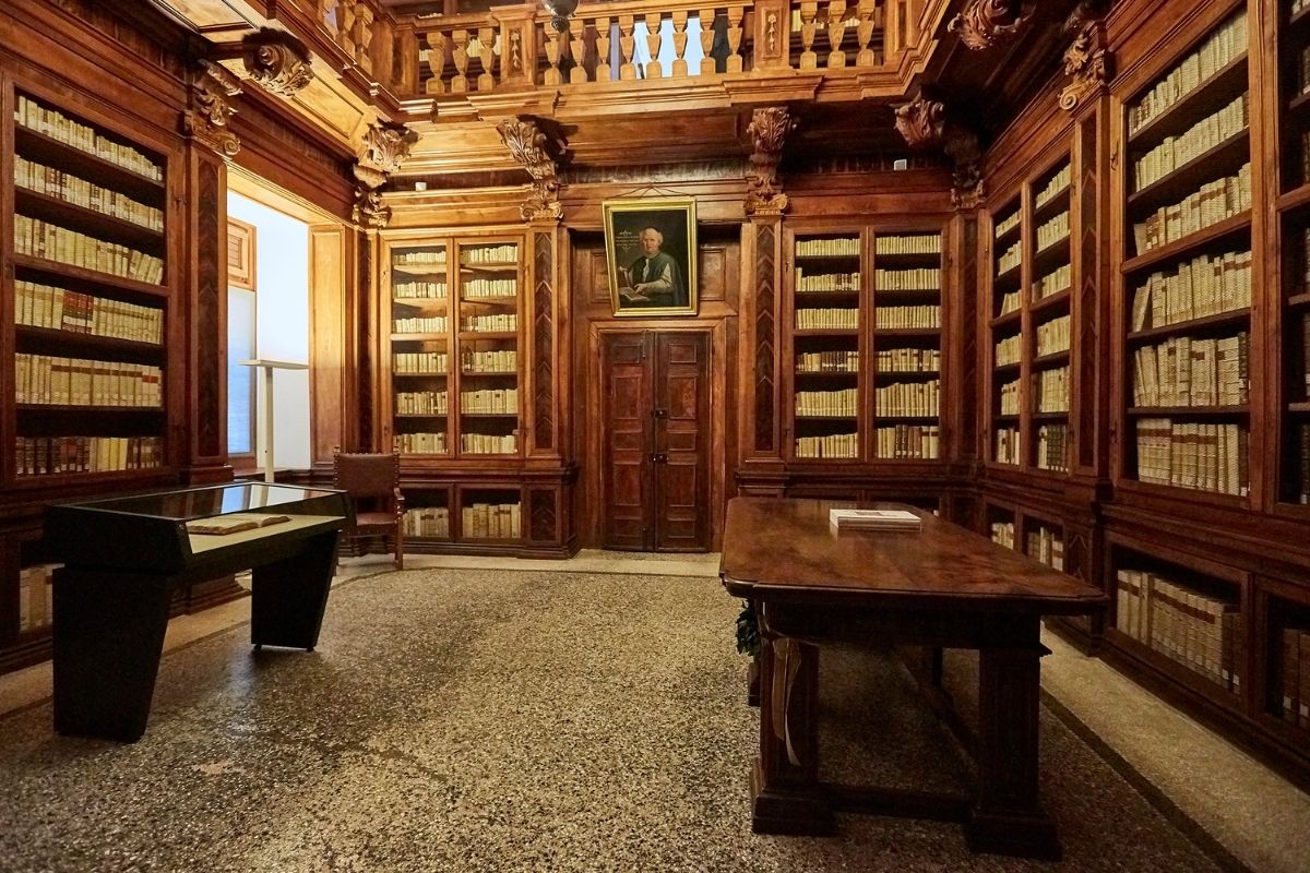 Interni della Biblioteca Guarneriana, mettendo in risalto l'architettura e i manoscritti