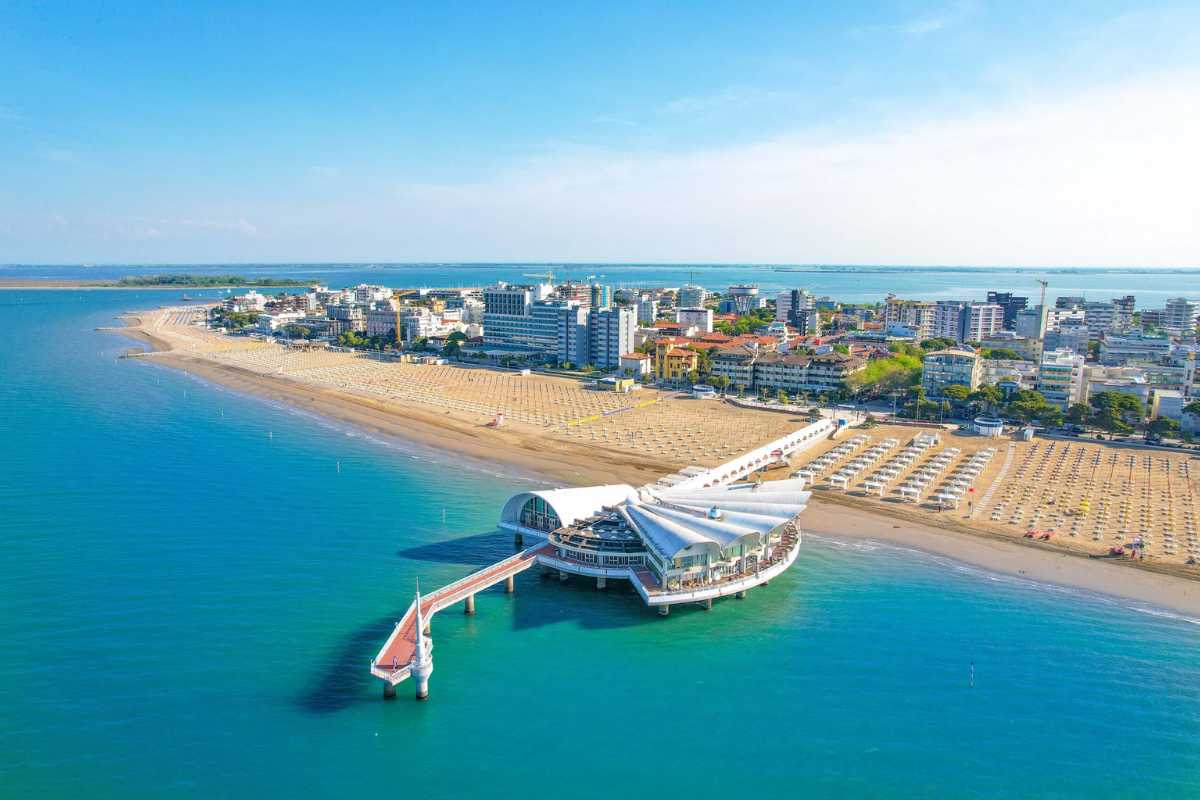 Spiaggia di Lignano Sabbiadoro durante il tramonto, con persone che si godono il mare